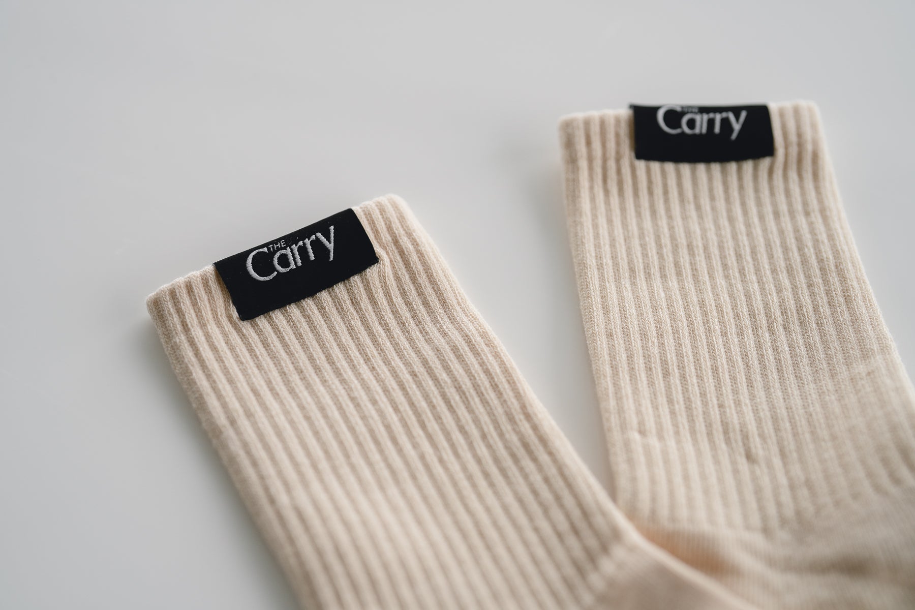 Beige socks with 'The Carry' label on a light gray background