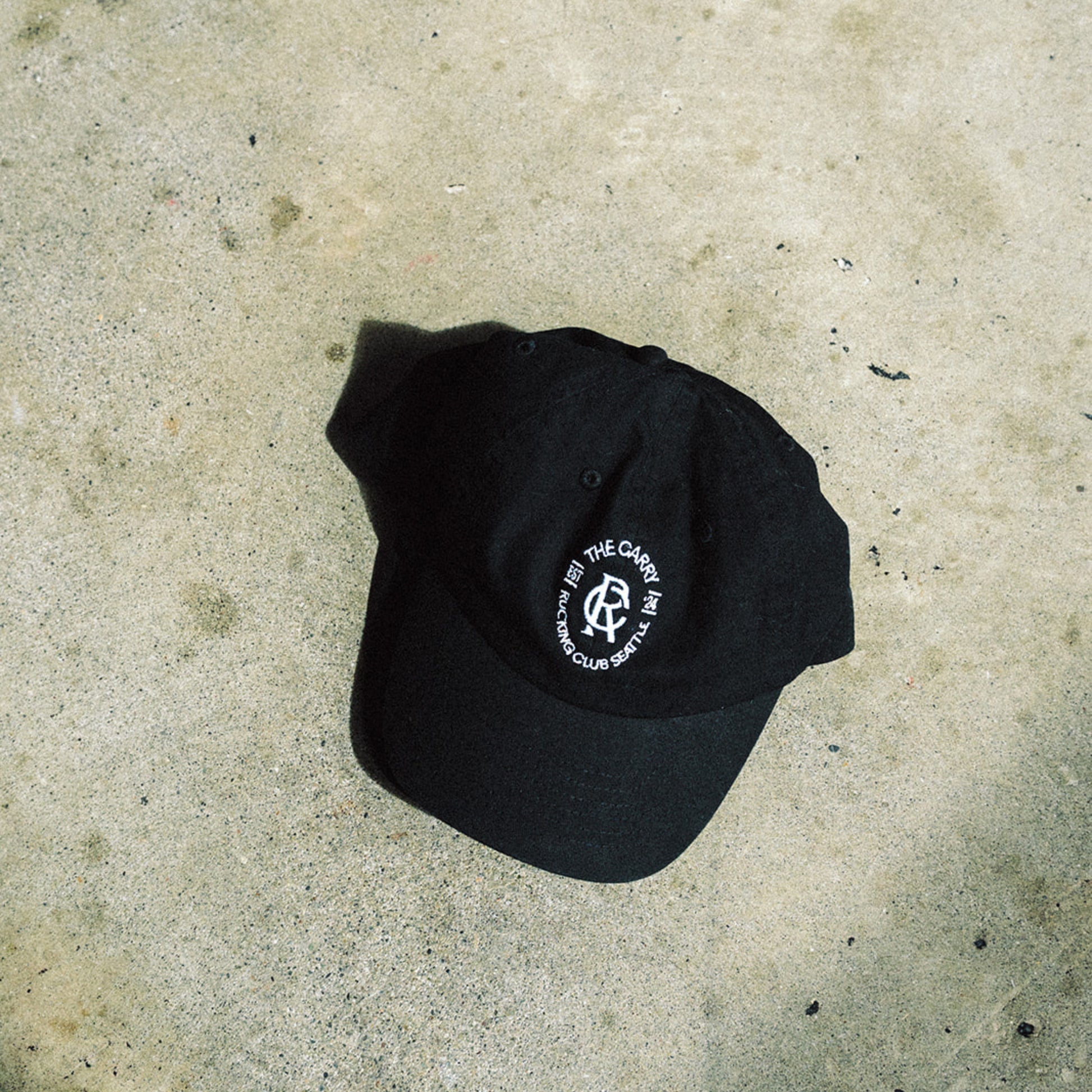 The Carry Rucking Club black lifestyle hat on concrete floor