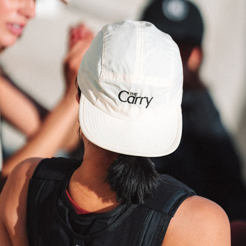 Person wearing a white cap with 'The Carry' logo, blurred background