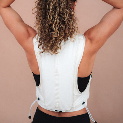 Woman wearing The Carry weighted vest in cream against a plain background, back view