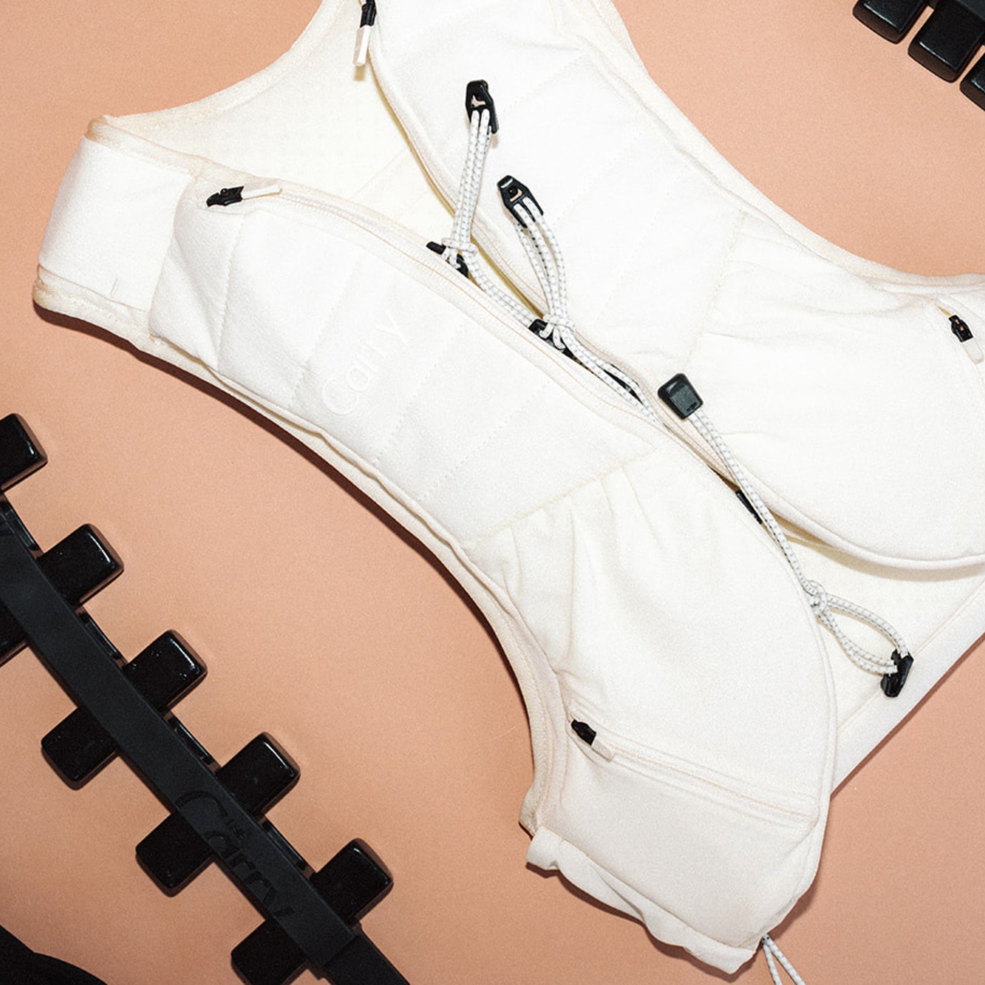 The Carry weighted vest shell in cream next to the adjustable weight system