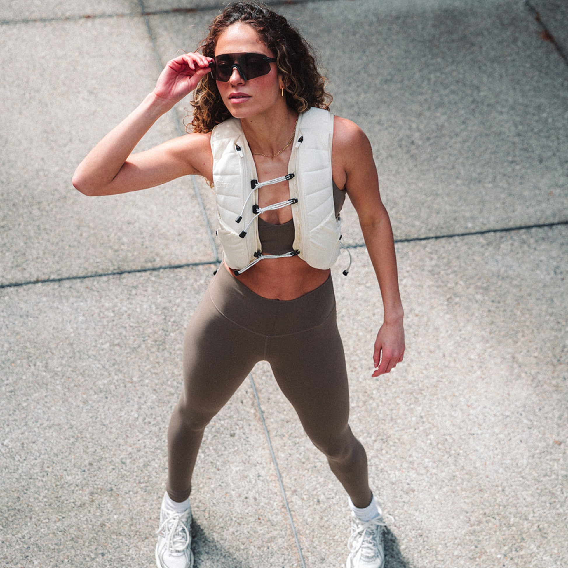 Woman wearing The Carry weighted vest in cream against a plain background in the city with a concrete backdrop