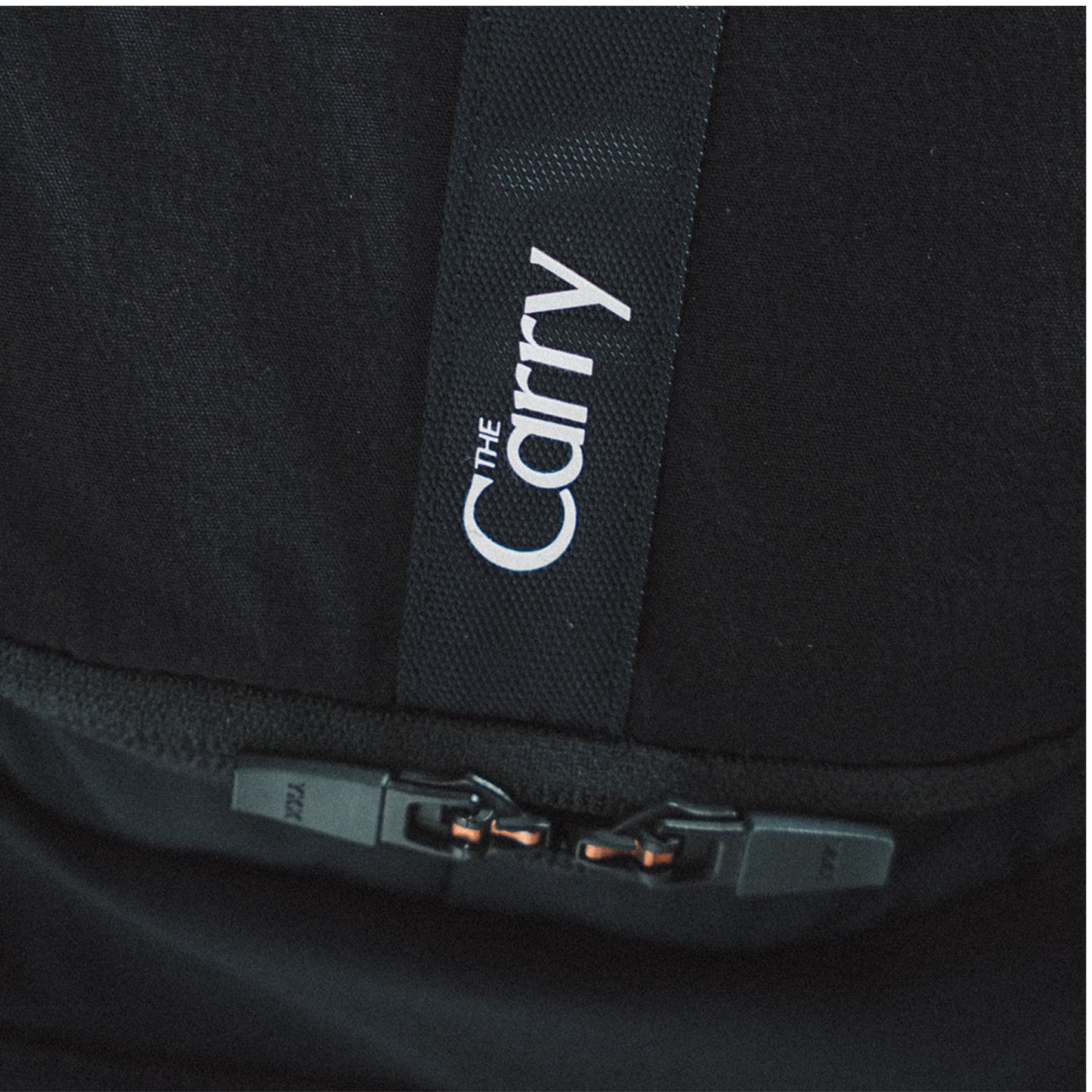 The Carry Vest shell in black, zoomed back pocket zippers and branding